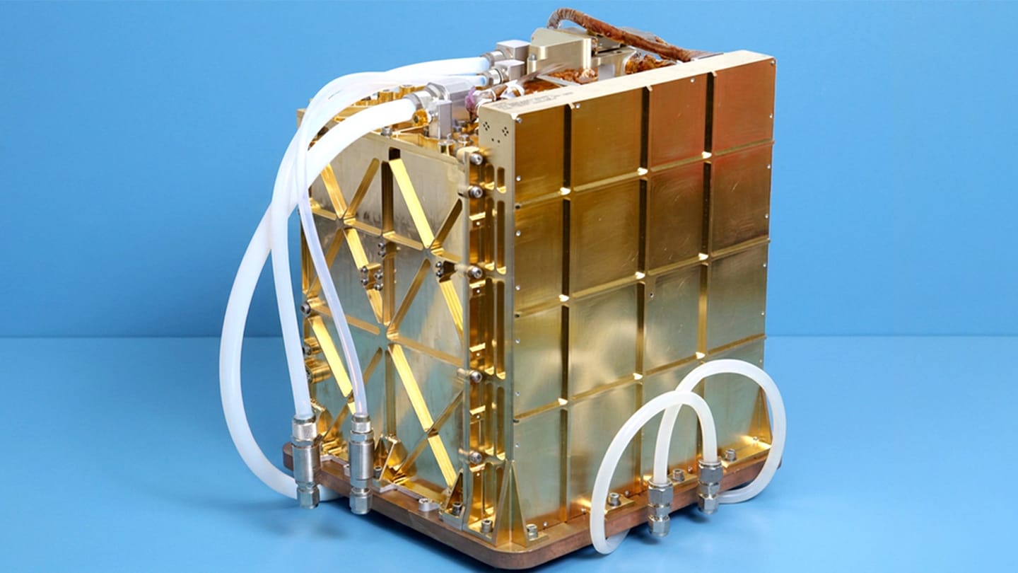 Gold-colored scientific apparatus with interlocking panels, tubing, and fittings set against a blue background