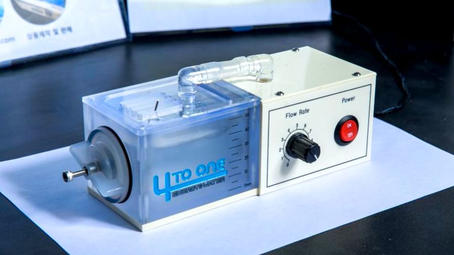 Laboratory benchtop pump labeled 'LTO ONE' with clear reservoir and adjustable flow-rate dial on a dark table surface